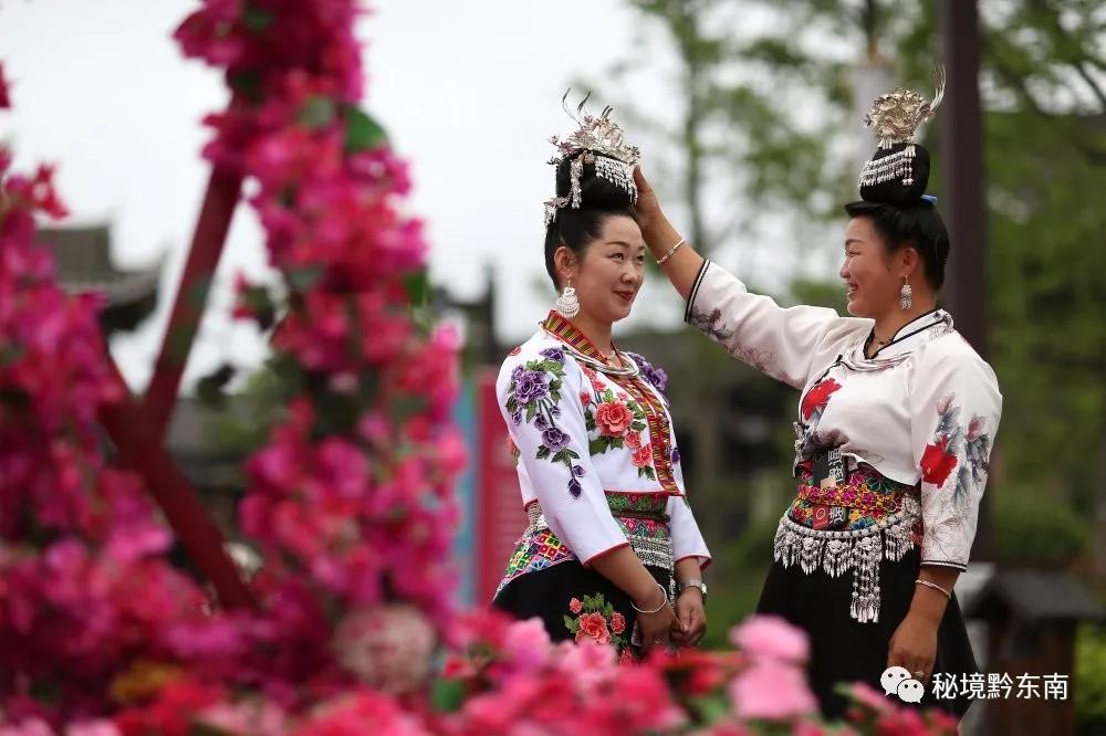 6月13日,身着盛装的苗族村民在贵州省丹寨县万达小镇景区整理银饰.