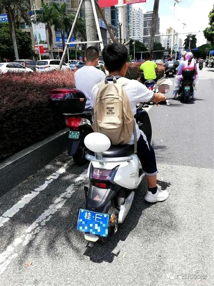 贵州路口由东往西左转弯车道有一名身穿校服的中学生不戴头盔骑摩托车