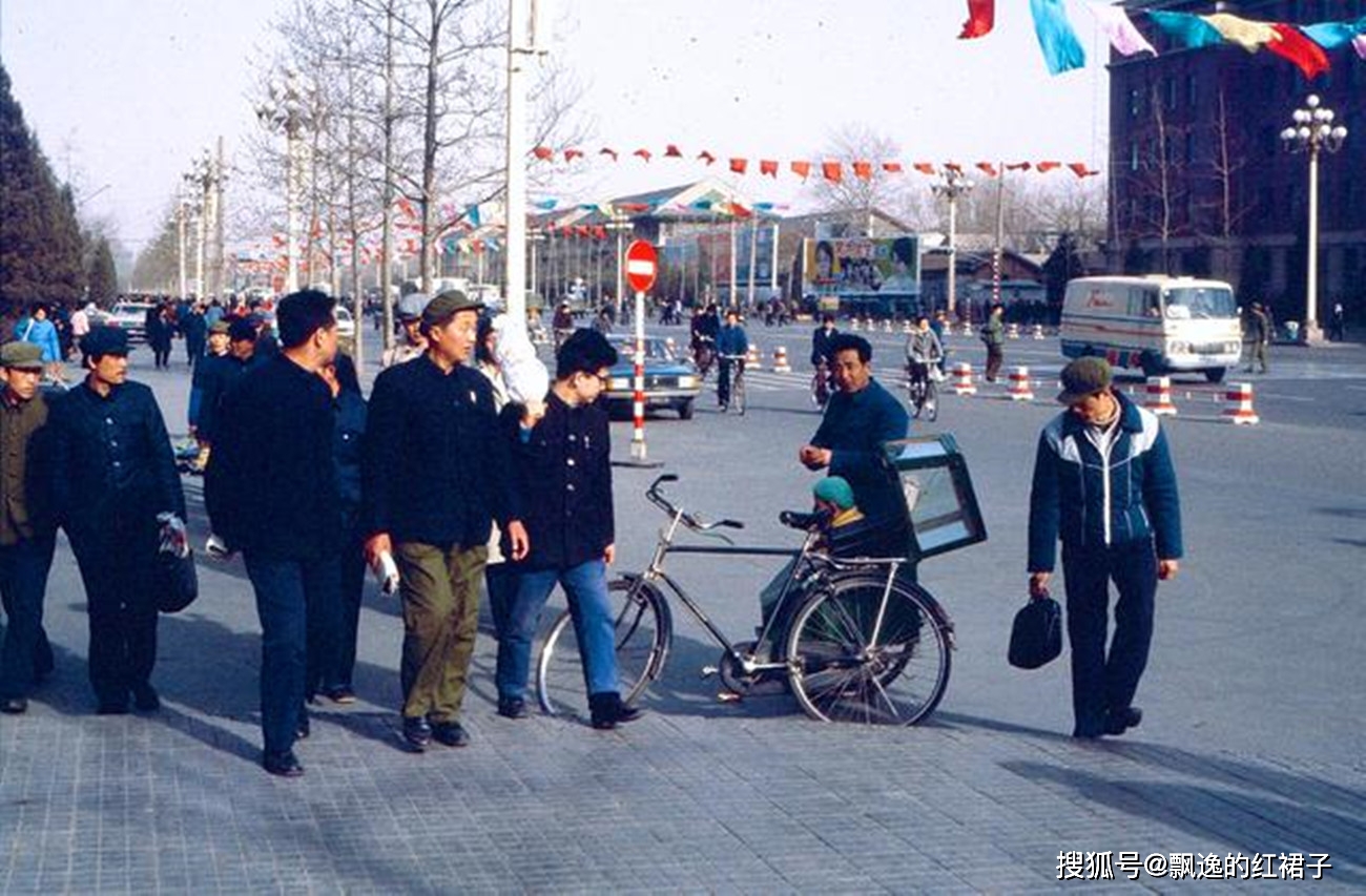 1983年的北京街景,一辆改装后的自行车右后侧加了一个挂斗,挂斗里坐了