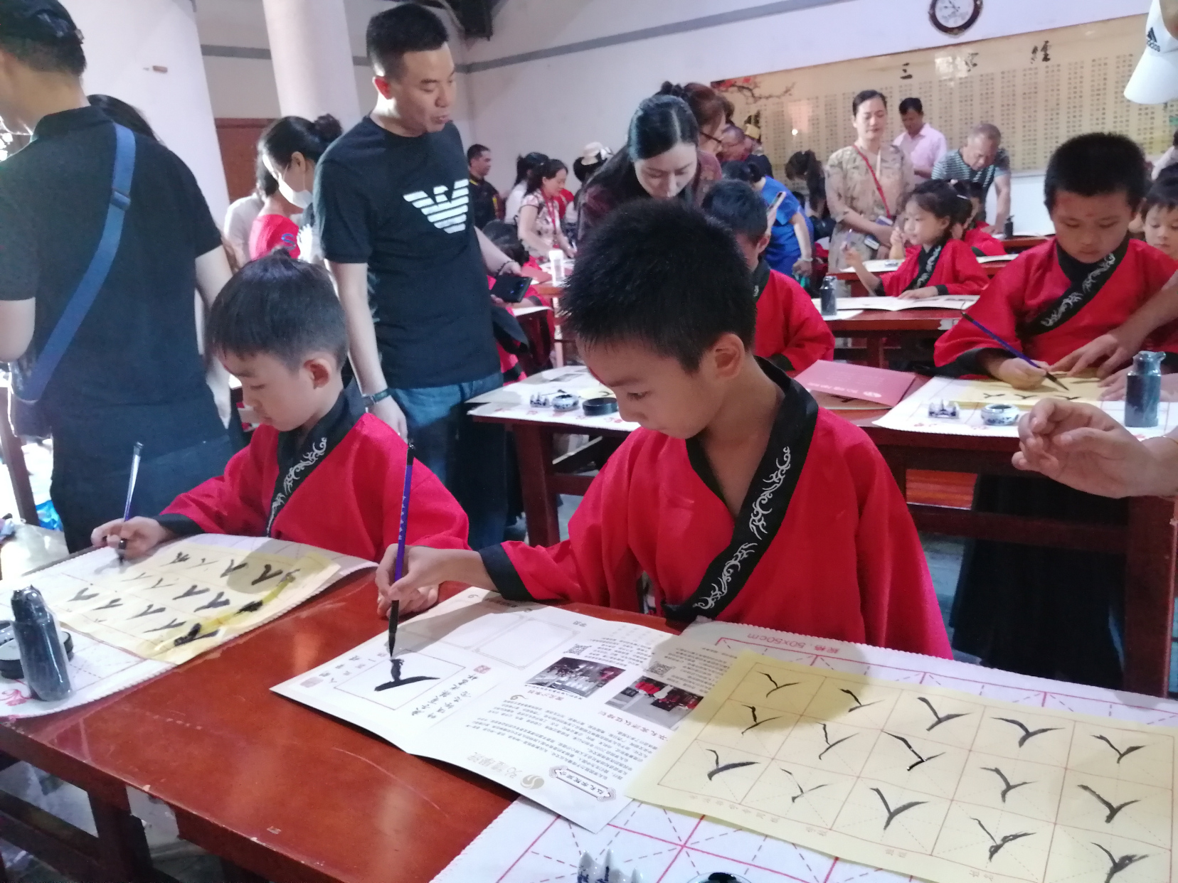 启智开笔礼有个"启蒙描红"环节,学童们拿起笔,开笔写人字