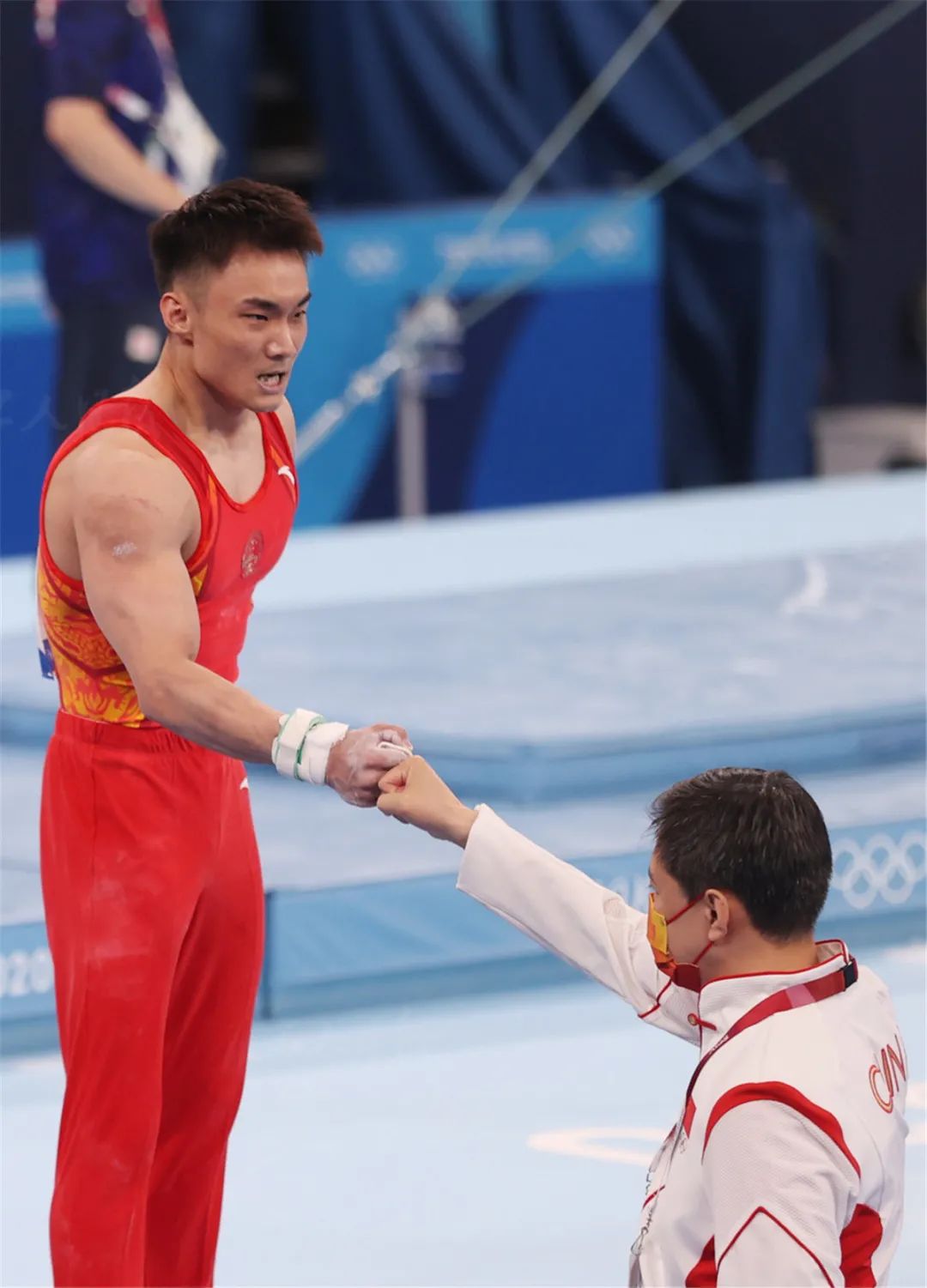 7月26日,在体操男团决赛中,孙炜(图左)在完成比赛项目后与教练击拳