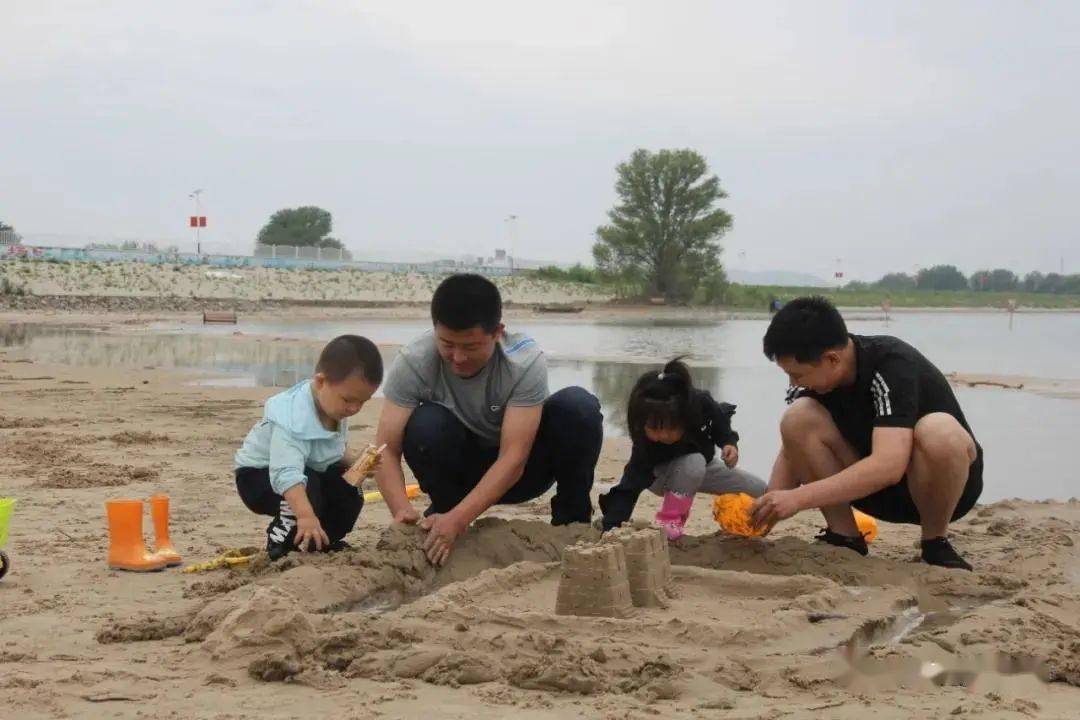 游客们在府西湖沙滩上堆沙堡