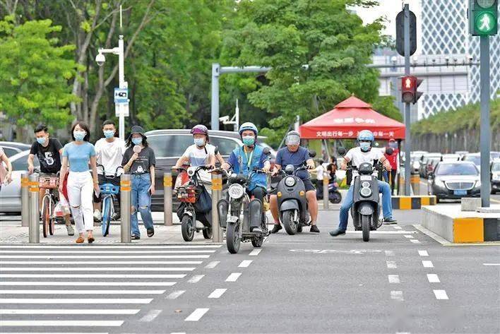 红灯路口,骑行的市民戴好头盔,遵守交通规则,按道行驶.