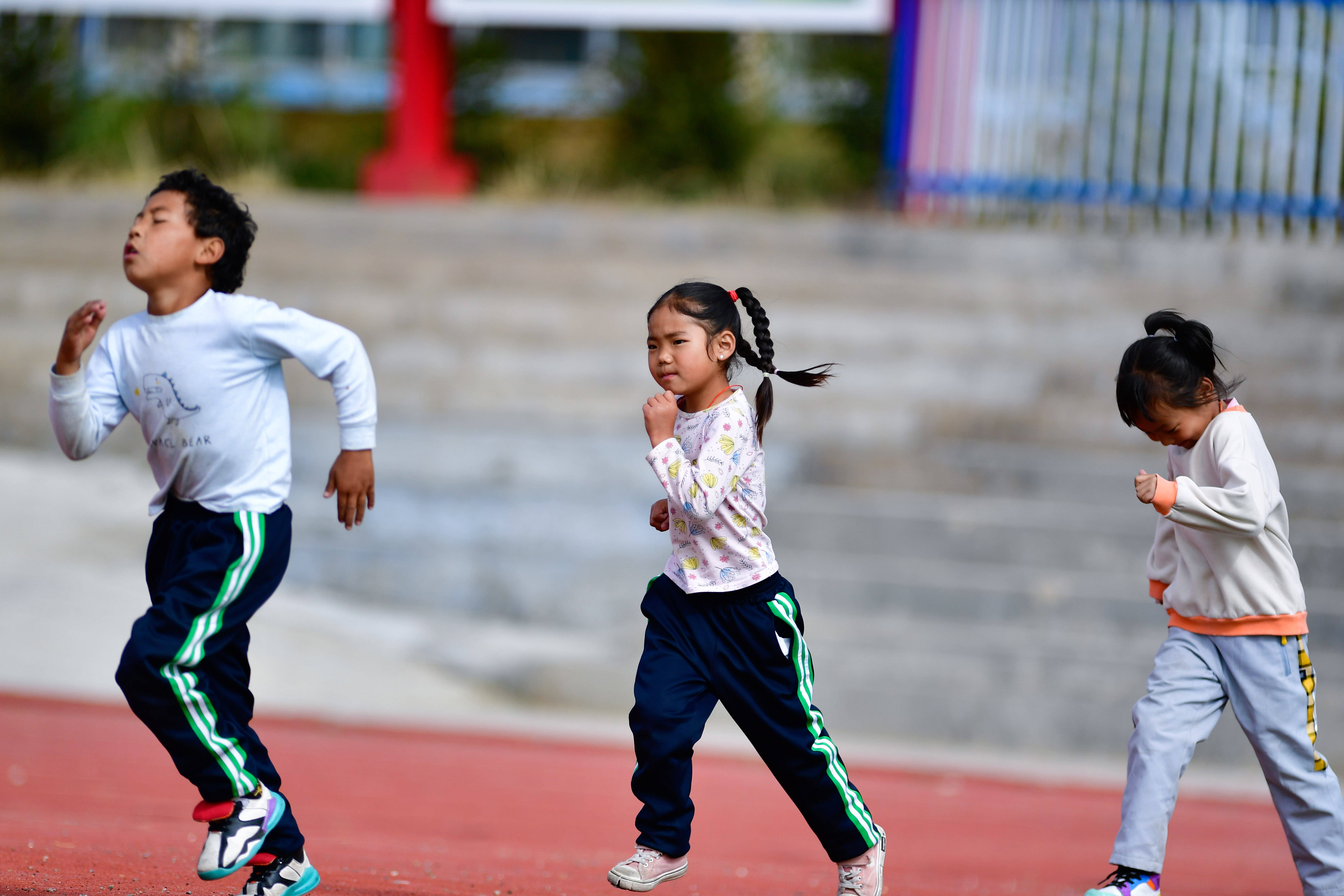 9月10日,一年级小学生旦增达卓(中)与同学们在进行跑步热身.