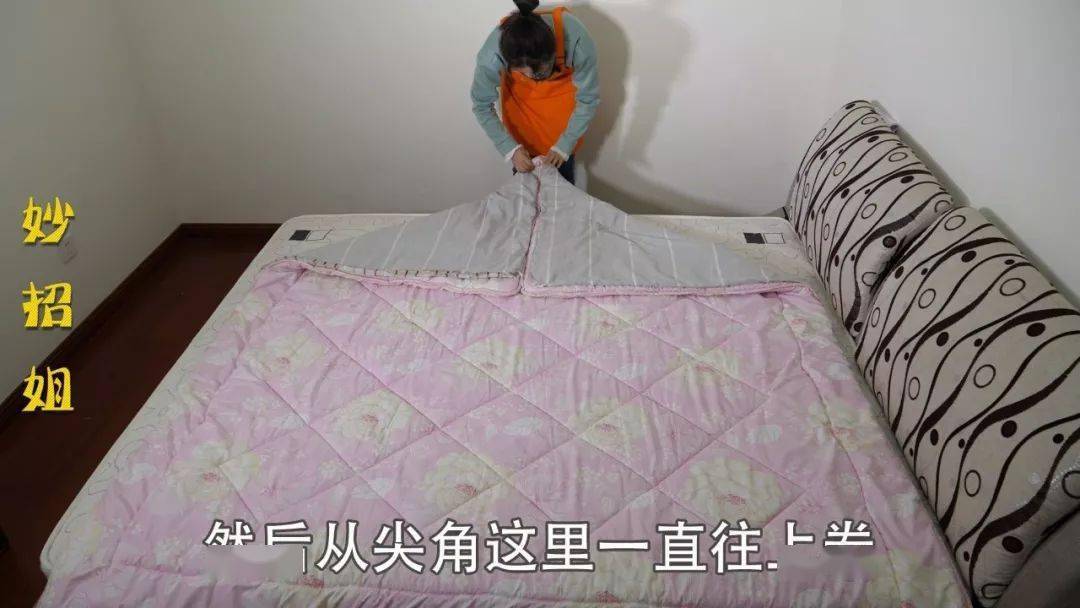 被子平铺好后,我们再抓起被子的两个角将它折成三角形,然后从尖角这