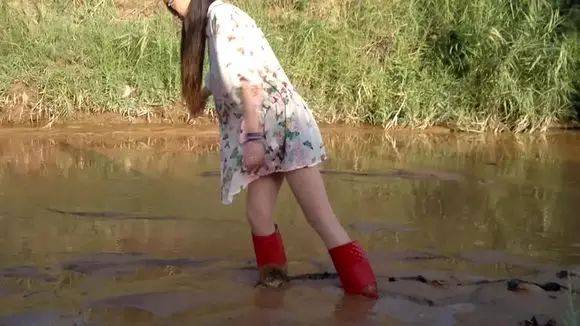 美女穿红色雨靴,泥河里摸鱼,拔不出腿