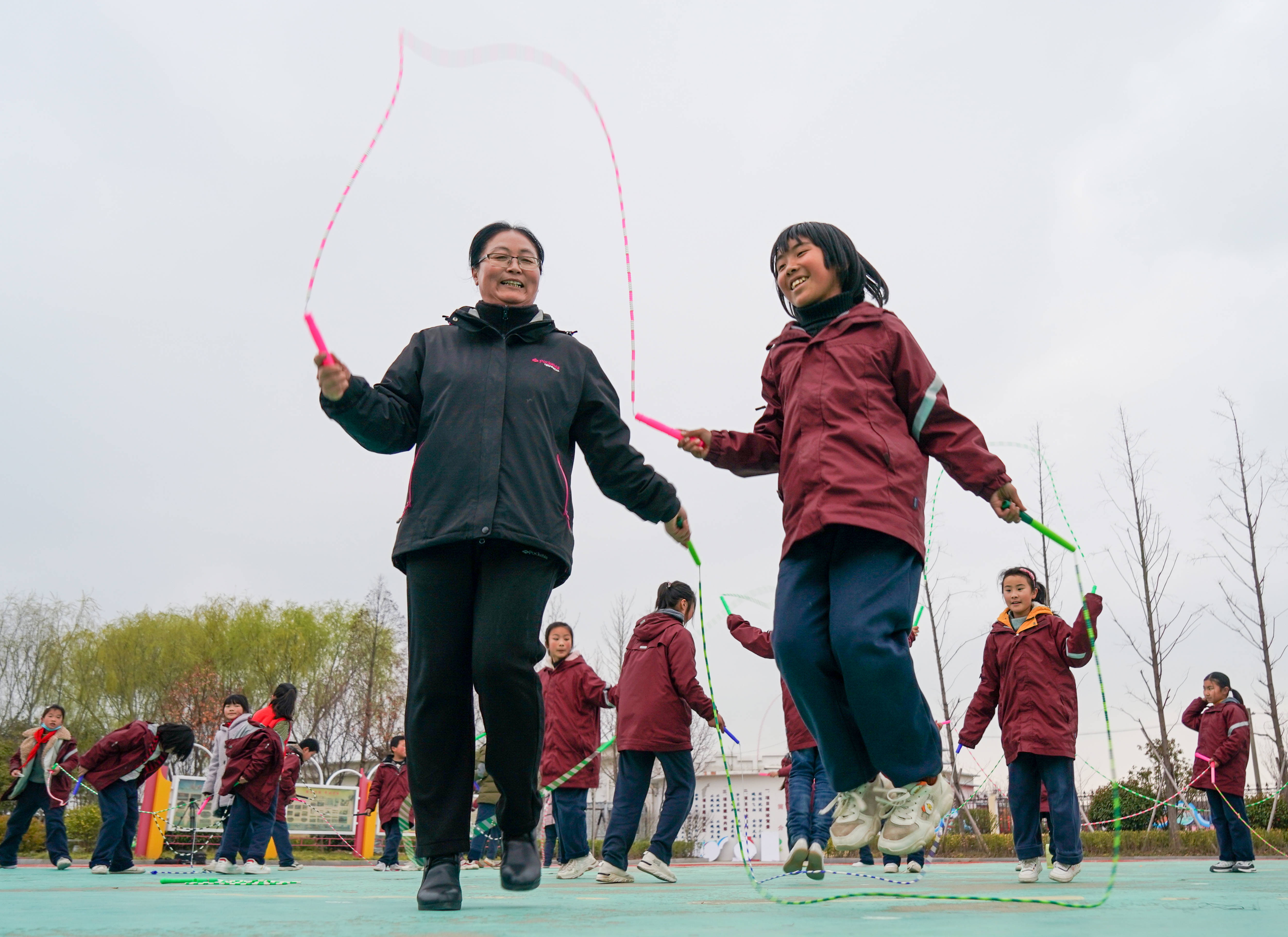 骑路小学刘彦老师(前左)和学生们在一起跳绳(3月9日摄).
