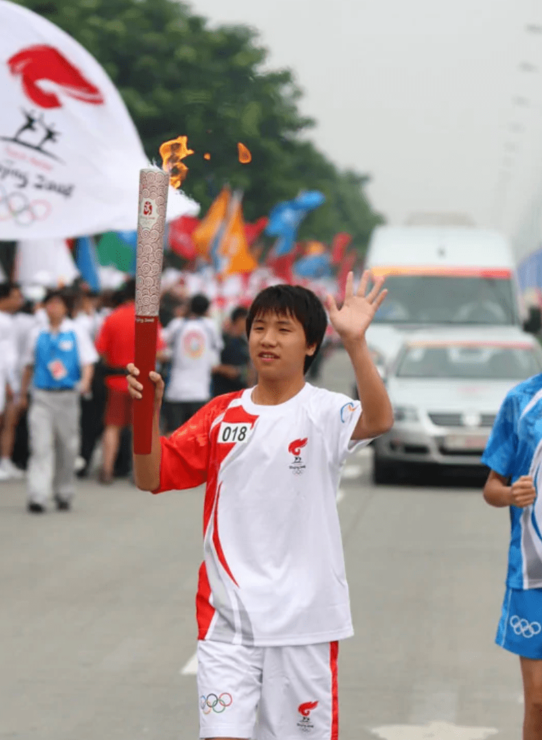 当第二天他高举圣火,挥舞着左手向道路两旁的人群致意.