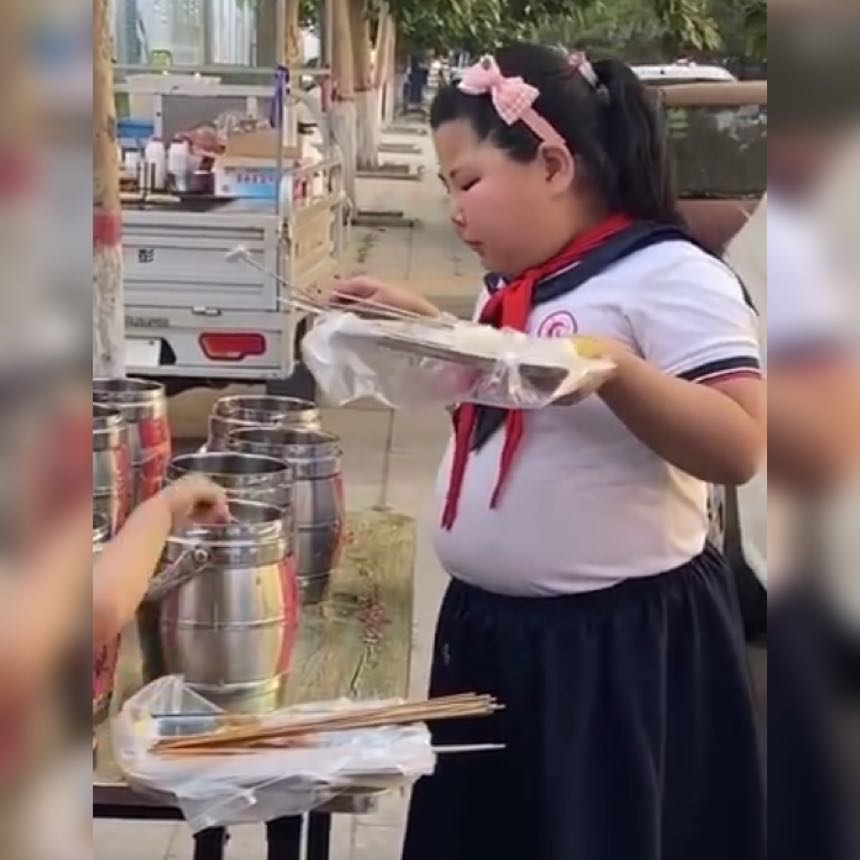 原创萌娃一手拿托盘一手拿沾串,吃得腮帮鼓鼓,香的表情令人垂涎三尺