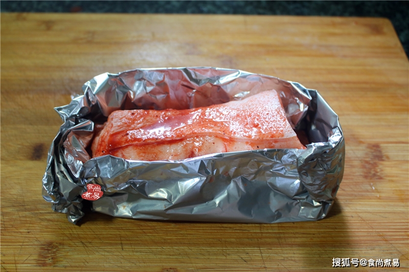 用锡纸把猪肉的四周以及底部围起来,猪皮向上,露出来,把包好的五花肉