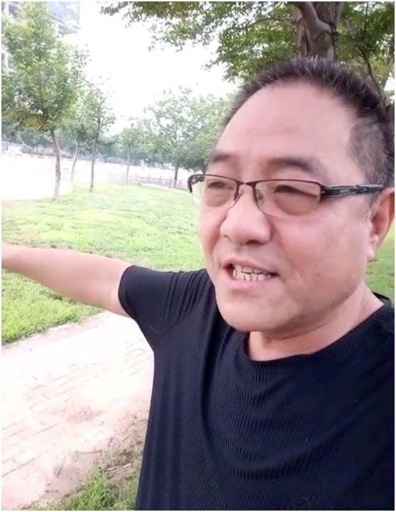 视频中,50岁的何铁红穿着黑色的短袖t恤,戴着眼镜,头发上已经出现了