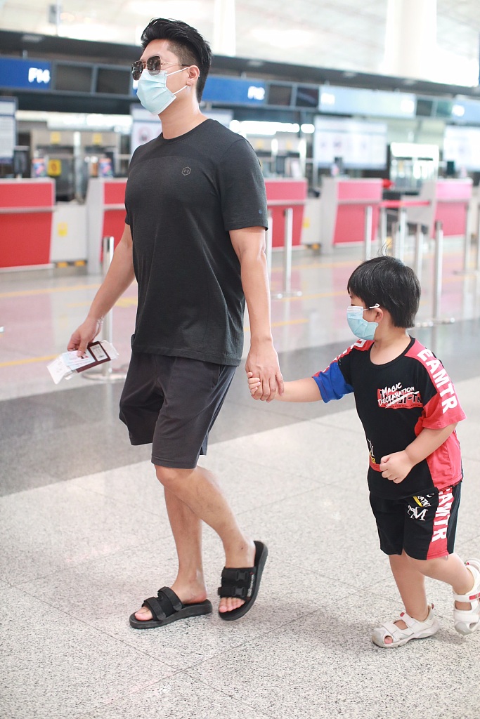 凌潇肃脚穿拖鞋拉着儿子搭机,造型随意. 凌潇肃牵着儿子,防护严密.