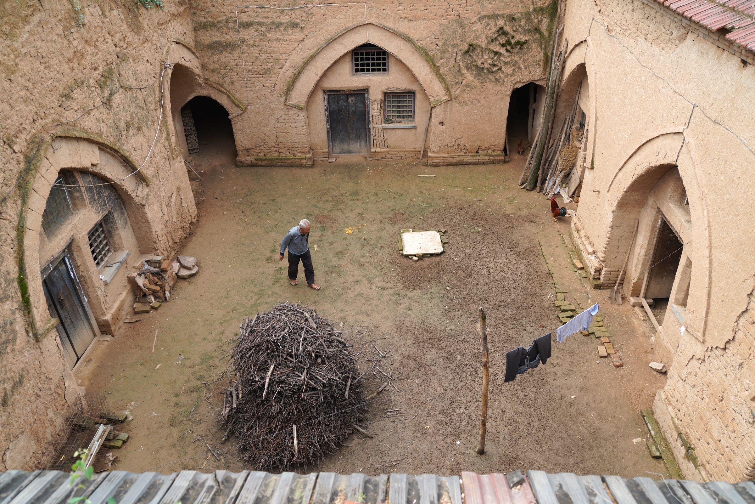 院子里,帮着儿子养牛,早上把牛拉到地面上去了,他下来打扫牛住的窑洞