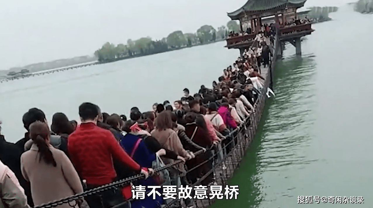 安徽一景区吊桥上挤满游客，人群晃晃悠悠，吊桥弯曲不堪