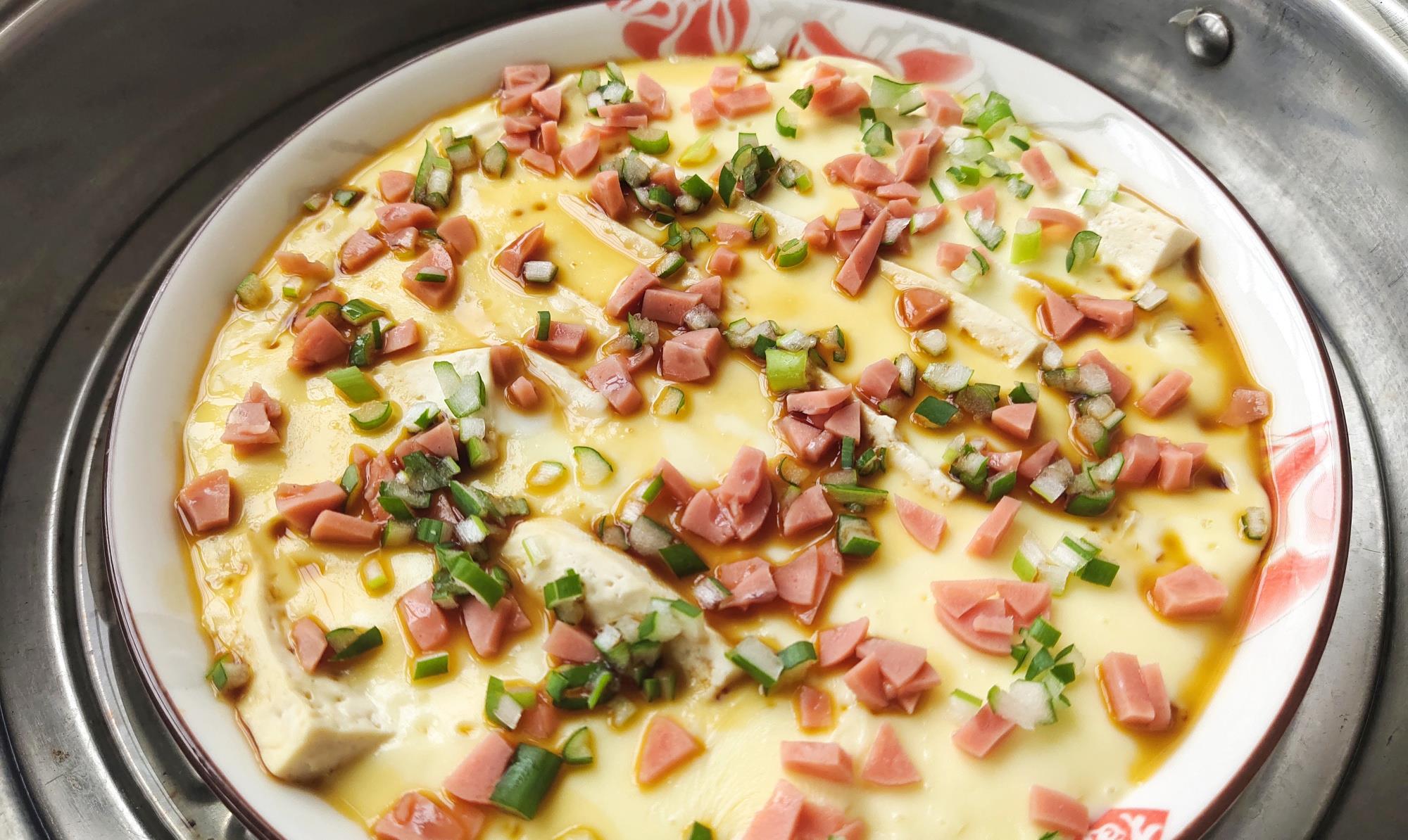 9,蒸10分钟后,把火腿肠和葱花撒在表面,加上1勺生抽,继续蒸1分钟,关火