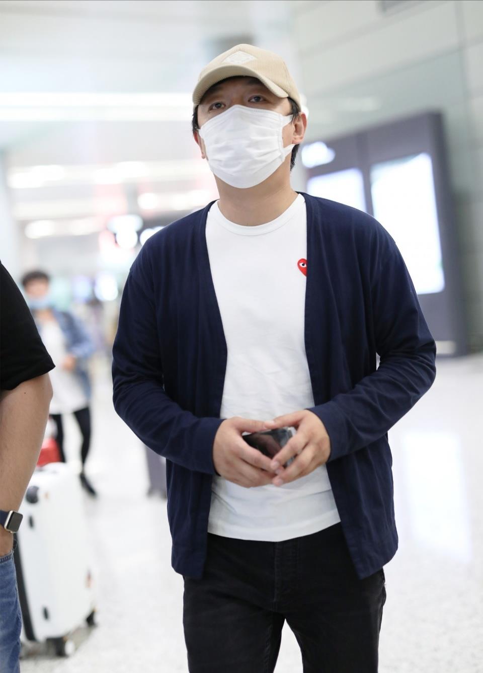 黄渤一身休闲装现身机场,内穿白色t恤,外搭深蓝色薄衫,下身穿黑色休闲
