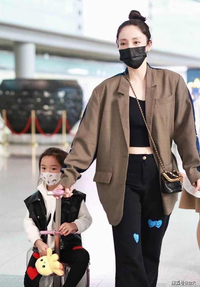 双手41岁董璇带女儿走机场！穿露腰短上衣不怕冷，被女儿环抱好亲密