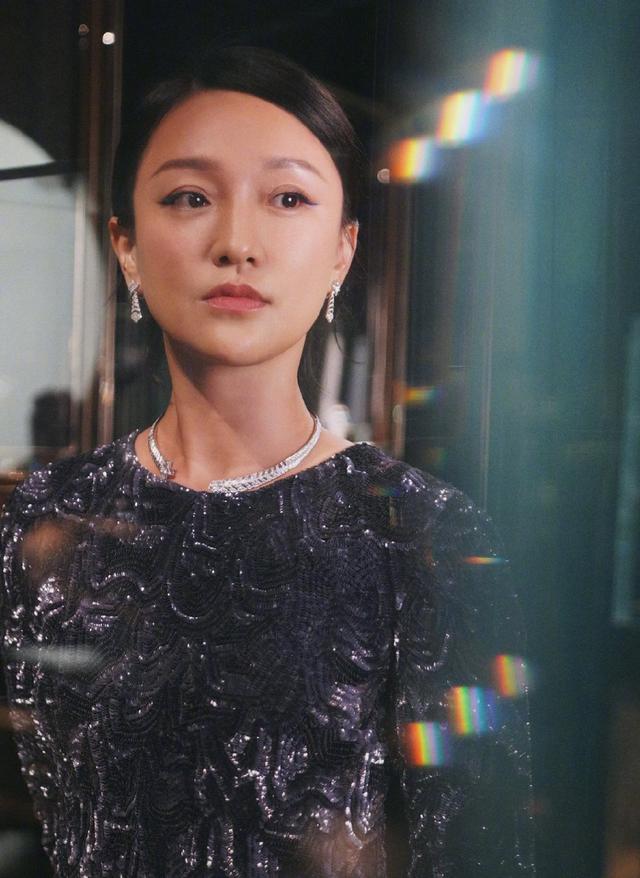 本人周迅纯黑亮片衫神情严肃，一展优雅成熟气质，上挑眼线更添娇媚