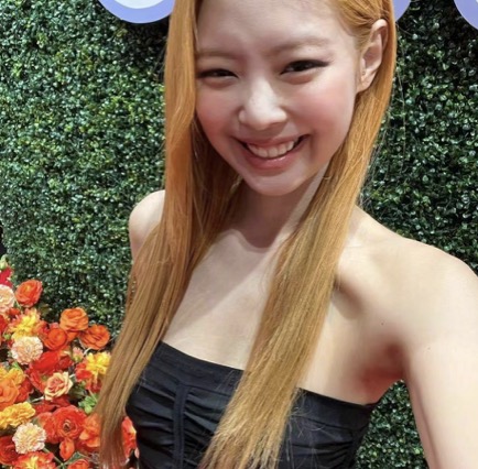 从照片中可以看出,jennie穿着一件黑色褶皱连衣裙,一头浓密的橙色头发