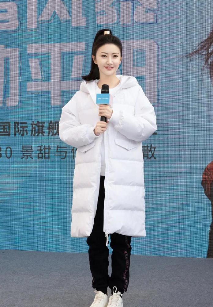 在该活动的现场景甜扎着单马尾,穿着一件较为宽大的白色羽绒服将整个