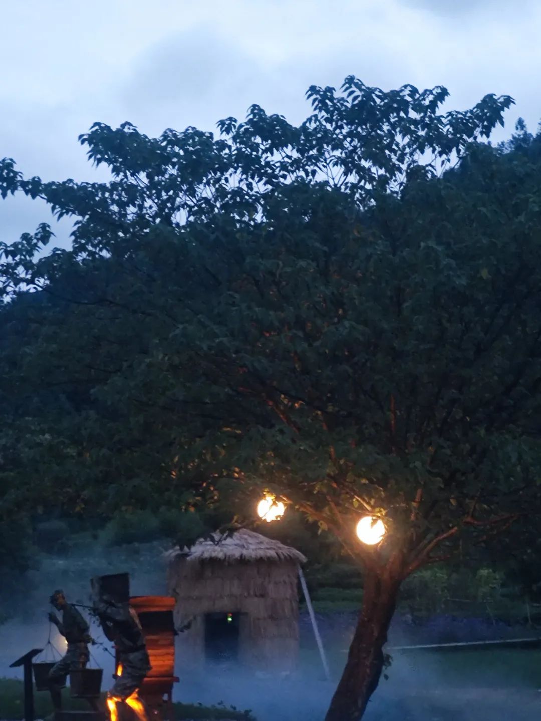 湖岸边烟雾袅袅,月亮灯泛起微弱的暖光,照亮了一旁的茅草屋.