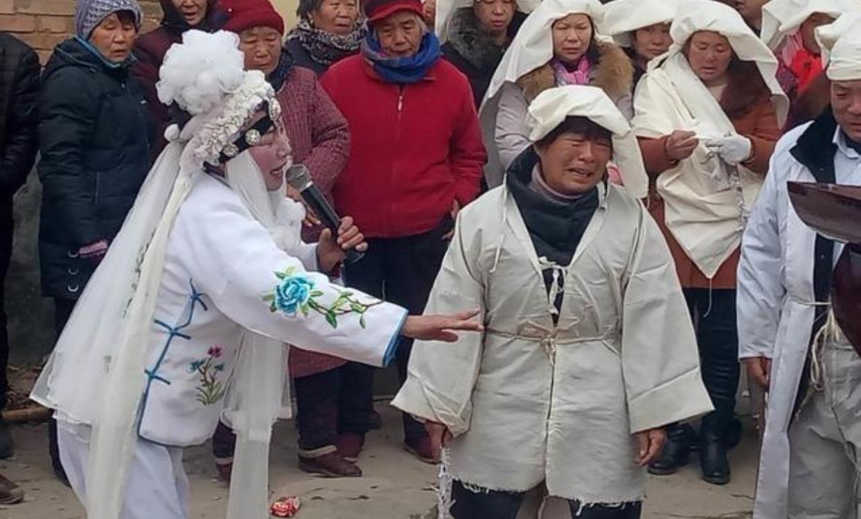 河南,一场丧事正在举行,一位身着孝衣的女子,双眼含泪,跪在灵柩前,放
