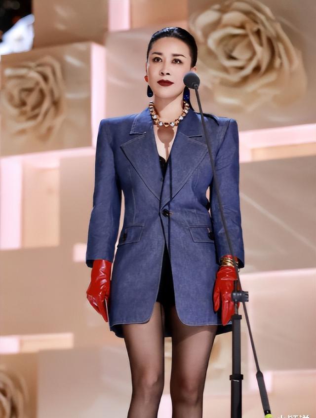 那英今天穿着一身深蓝色的牛仔套装,戴着一双红色的皮手套,脖子上挂着