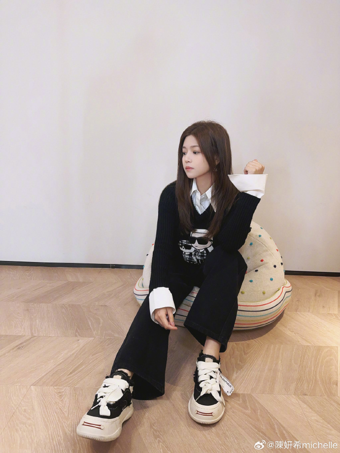 画面中的陈妍希穿着黑色的针织毛衣,搭配同颜色的牛仔裤,脚踩着运动鞋