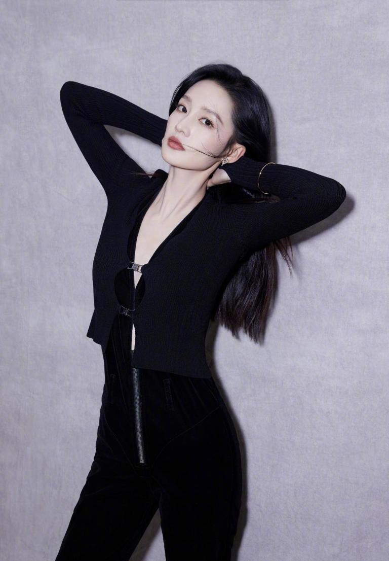 李沁的长发飘扬,他身穿深v黑色上衣,手捧鲜花看着镜头,他大胆又美丽