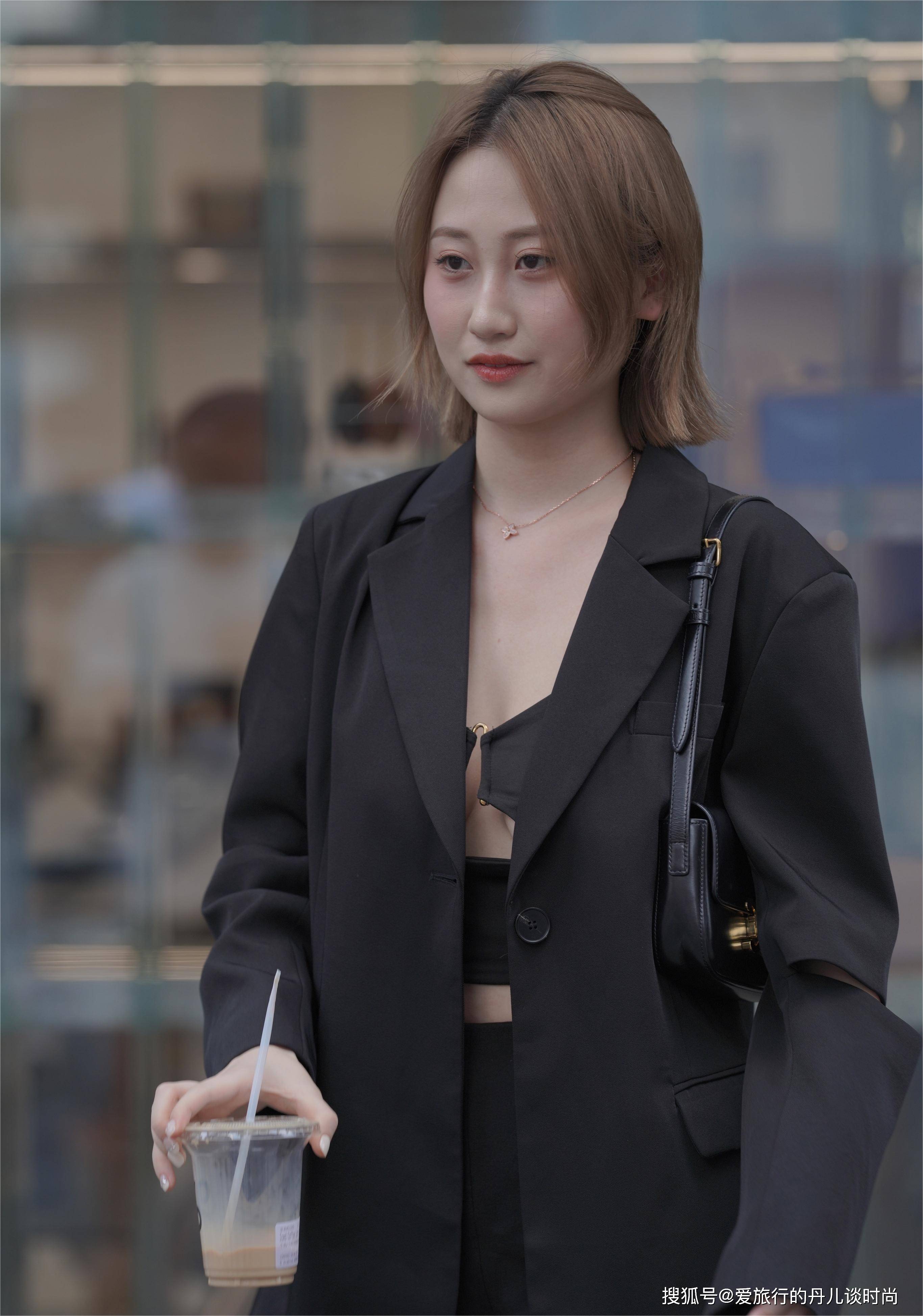 小姐姐身穿黑色长款西服内搭黑色吊带和黑色短裤,西服后背拼接设计