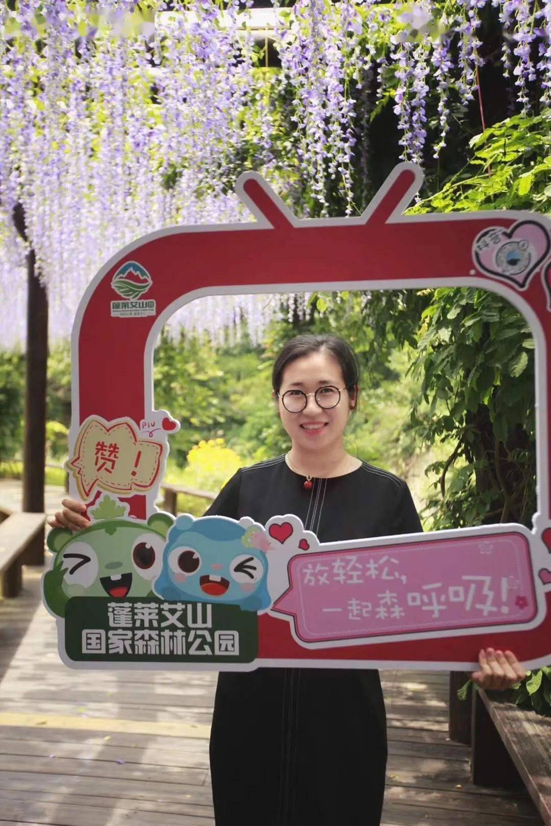 手持印有蓬莱艾山logo和森呼吸宣传语的网红拍照kt版相框拍照分享朋友
