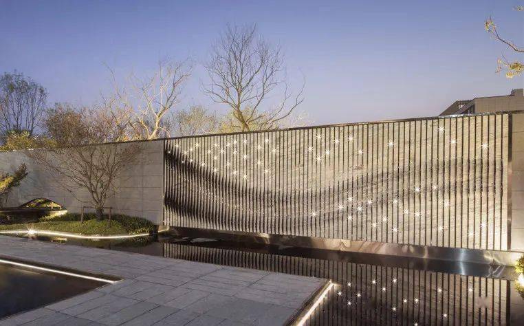 面饰灰色真石漆的水泥加压板干挂而成的景墙散布着几十盏星星灯;黑