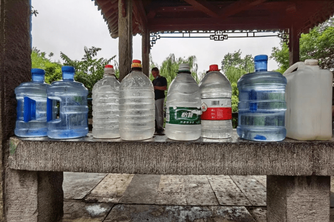 装满泉水的塑料桶排成一队,大爷大妈们接完水,在一旁拉拉家常,谁家有