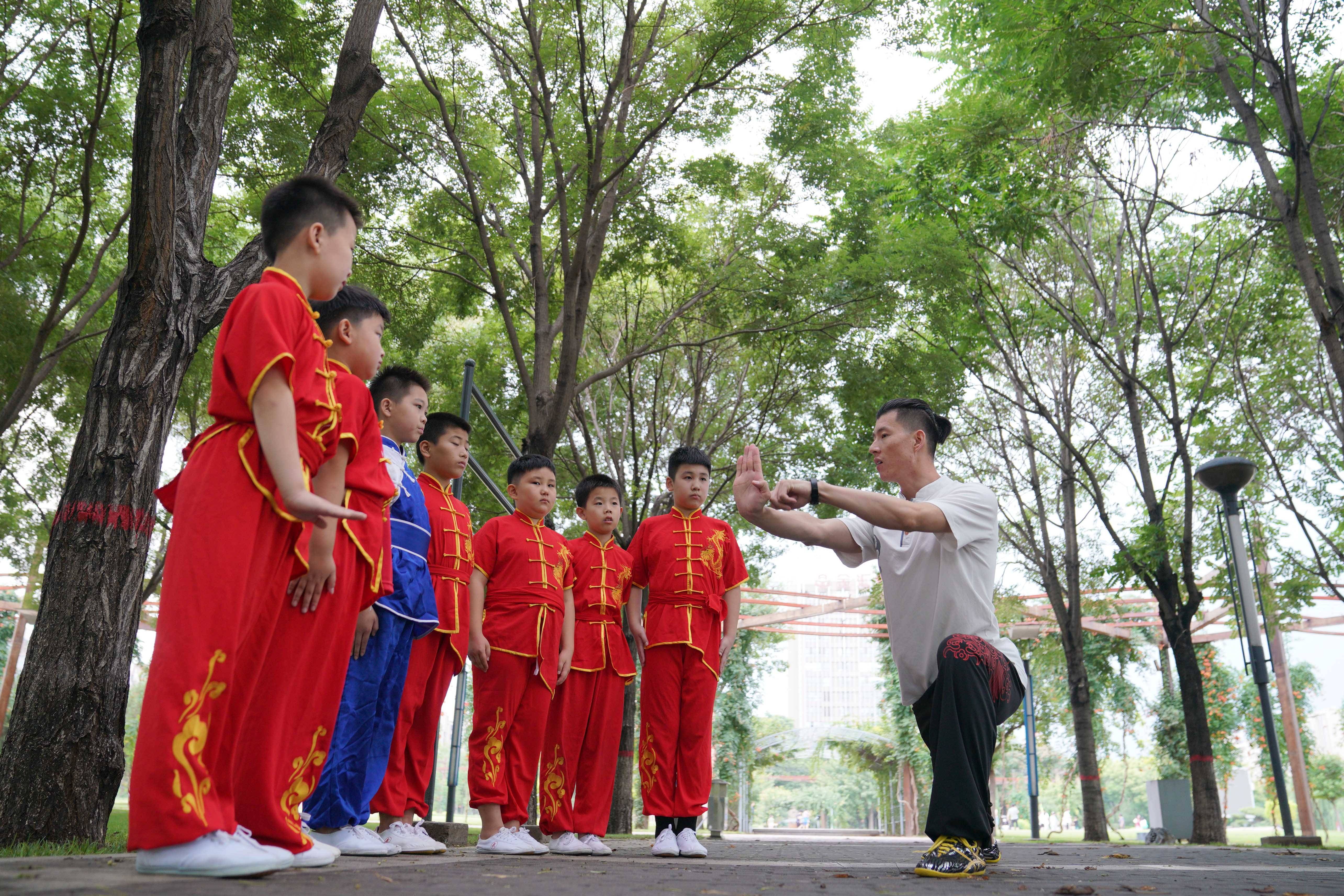 8月9日,武术教练刘超路(右一)为学生讲解武术动作