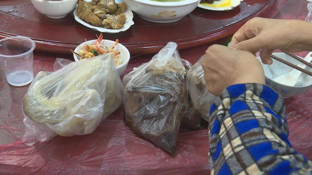 村民将未吃完的菜打包带走.