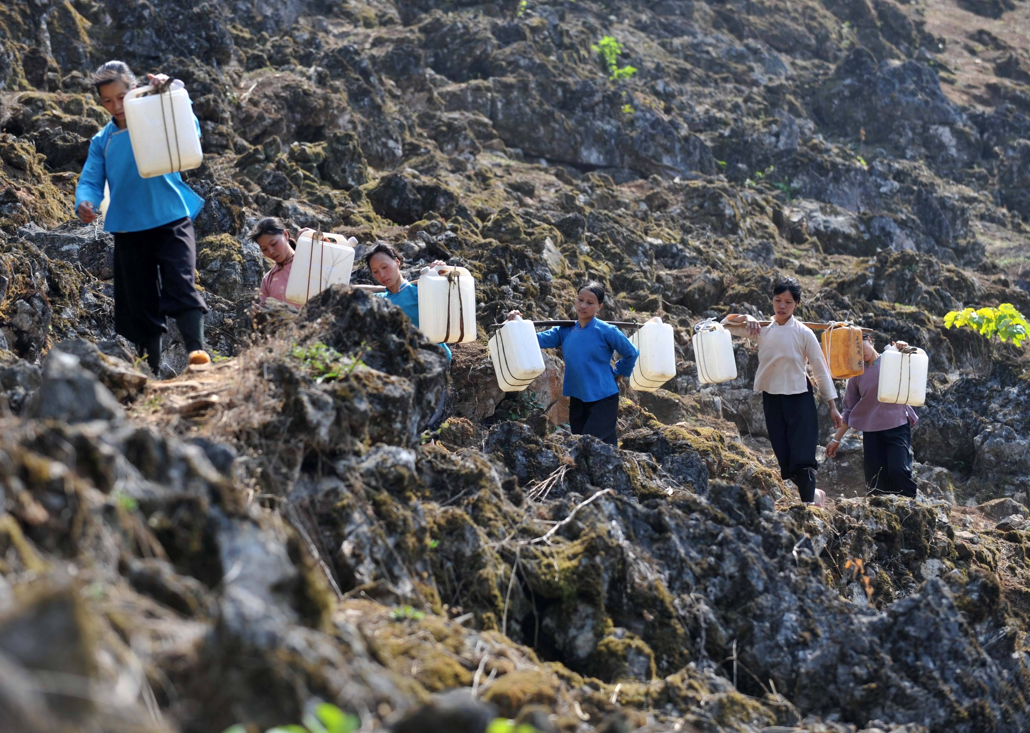 在廣西那坡縣百南鄉弄民村三支屯,村民挑著水走在山路上(2010年3月31