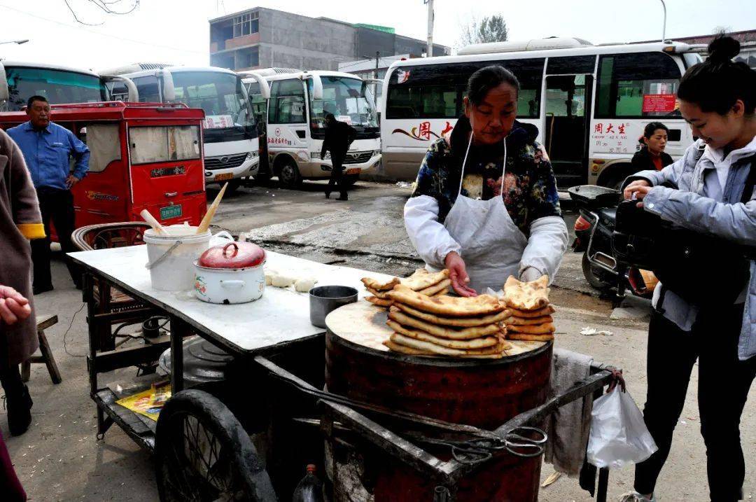 特制的手推车架着煤火烤炉,一人包馅一人开炉贴饼,烤好的烧饼摆在炉子