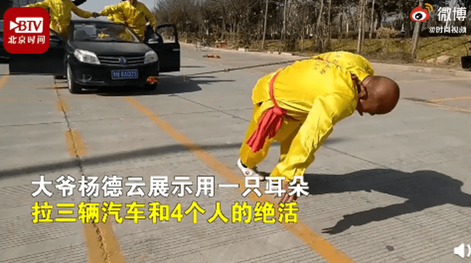 河南商丘，杨德云展示用一只耳朵拉三辆汽车和4个人的绝活，围观者看得目瞪口呆。