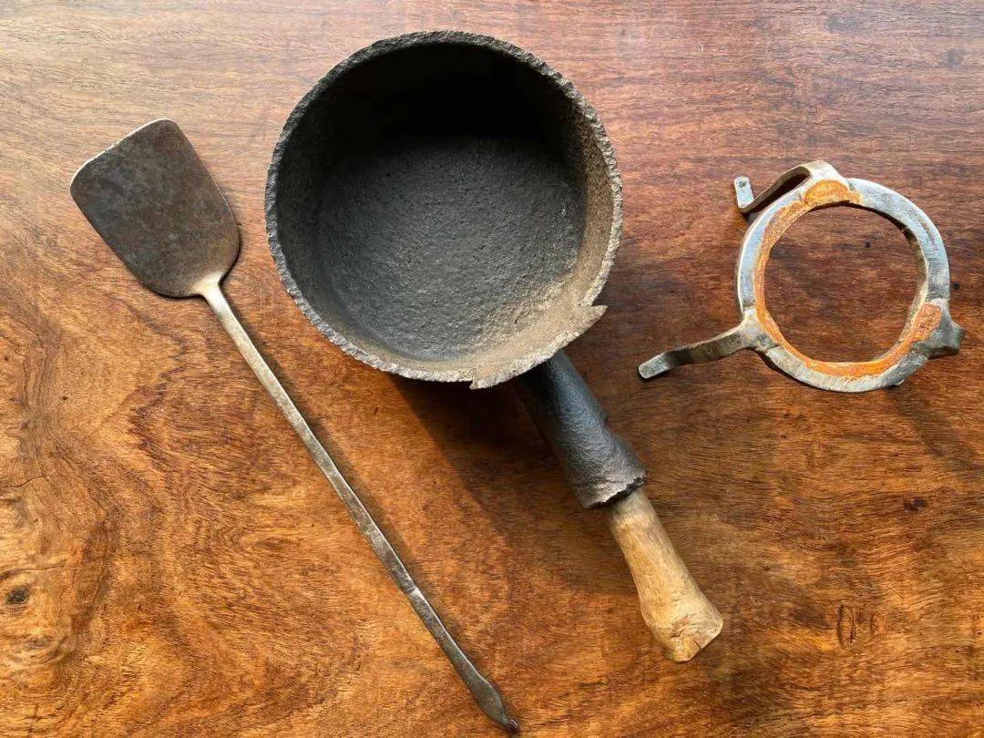 这是一组旧时代茶席或是食堂的老炊具,造型独特的老木柄铁锅,造型简约