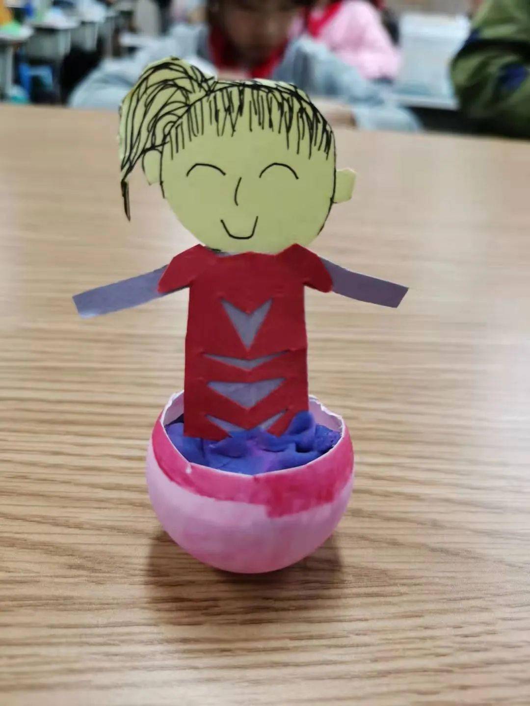 三年级同学进行了不倒翁的制作,他们利用半个乒乓球按上橡皮泥,再罩上