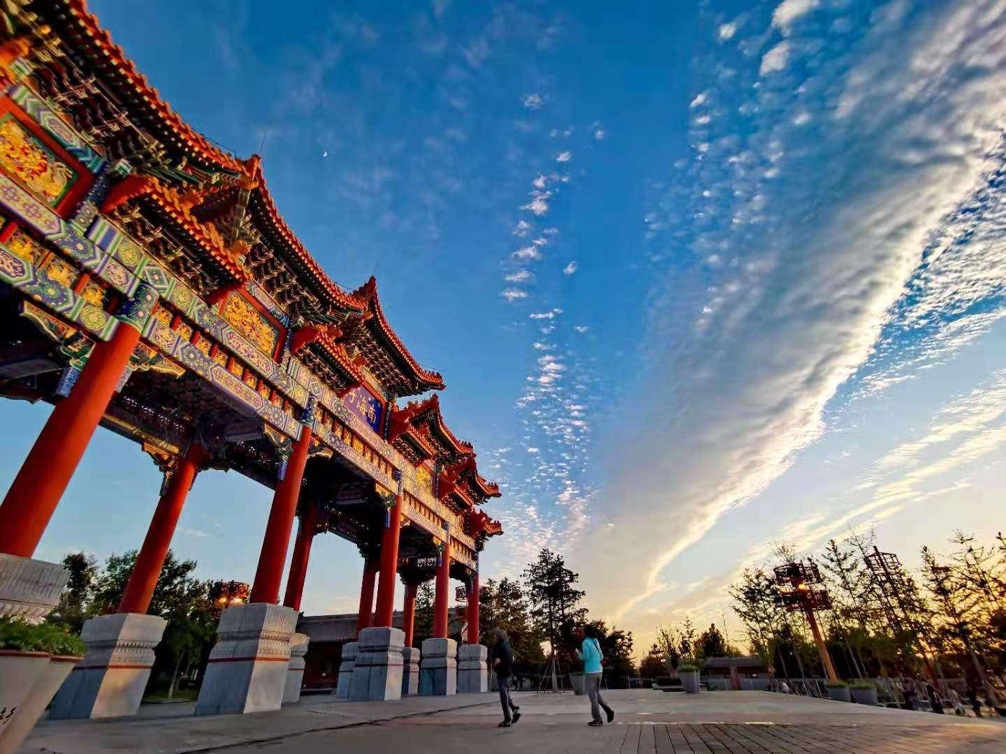 长云拖尾夕阳映照南海子公园北门的牌坊巍峨壮美