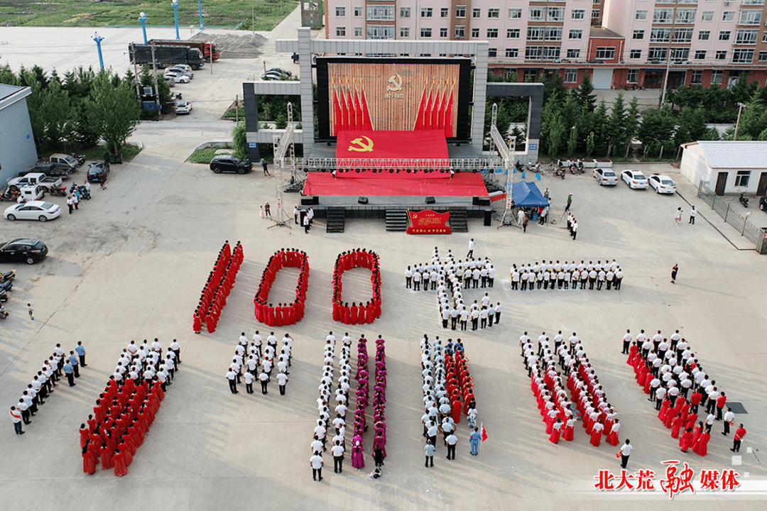鲜红的党旗,在擎旗手的托举下,跟随着方阵及拼有"100"和"七一"造型的