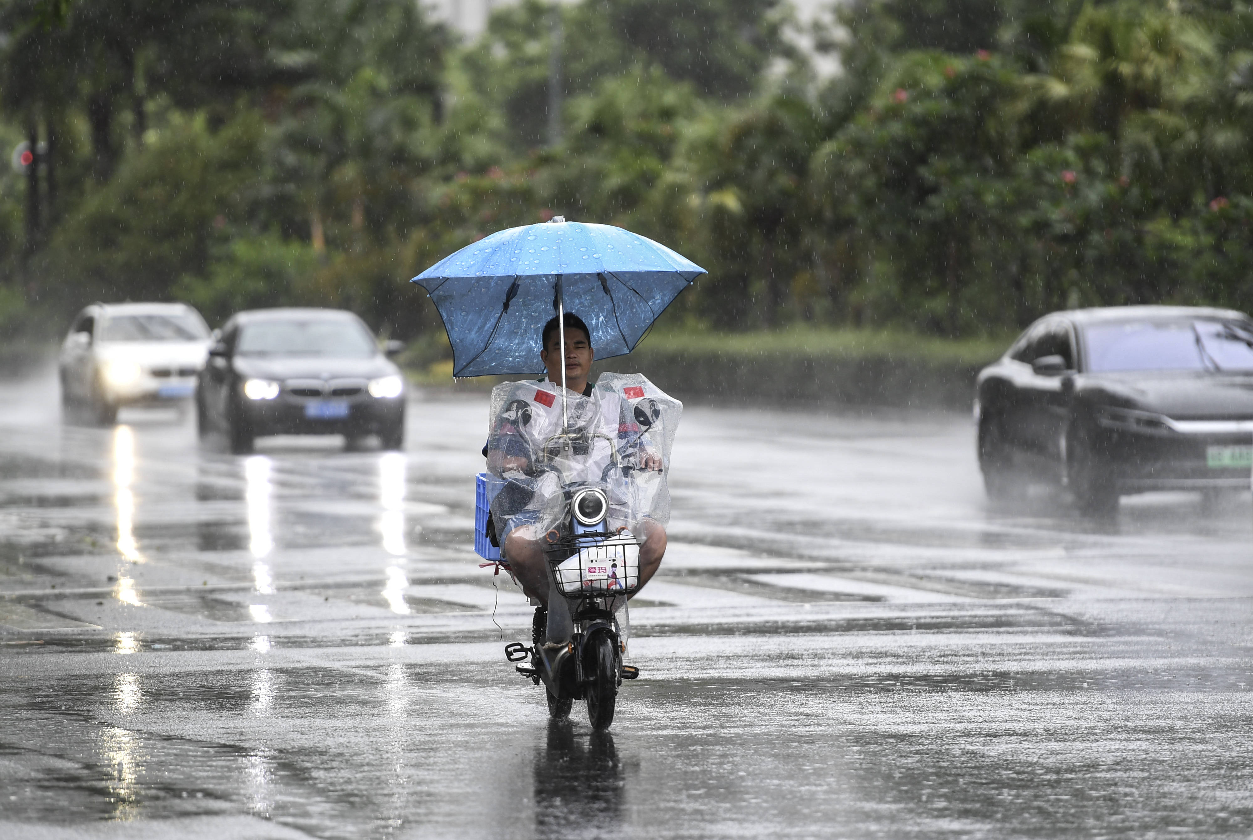 7月19日,居民骑着电动车在雨中前行
