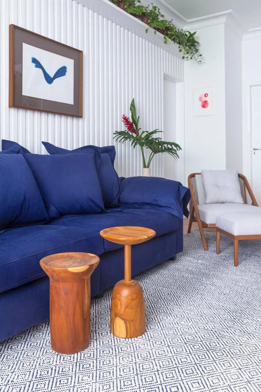 而是用一个迷你的小圆墩替代,宝蓝色的沙发与白色的竖条纹沙发背景墙