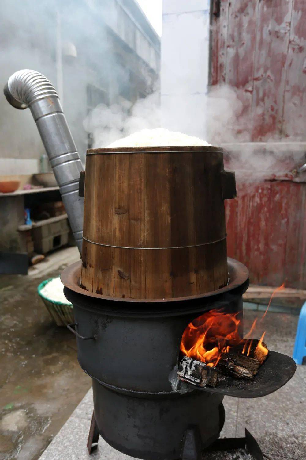 糯米慢慢开始蒸熟了随着柴火燃烧加热木桶放置在铁锅上将糯米放进木桶