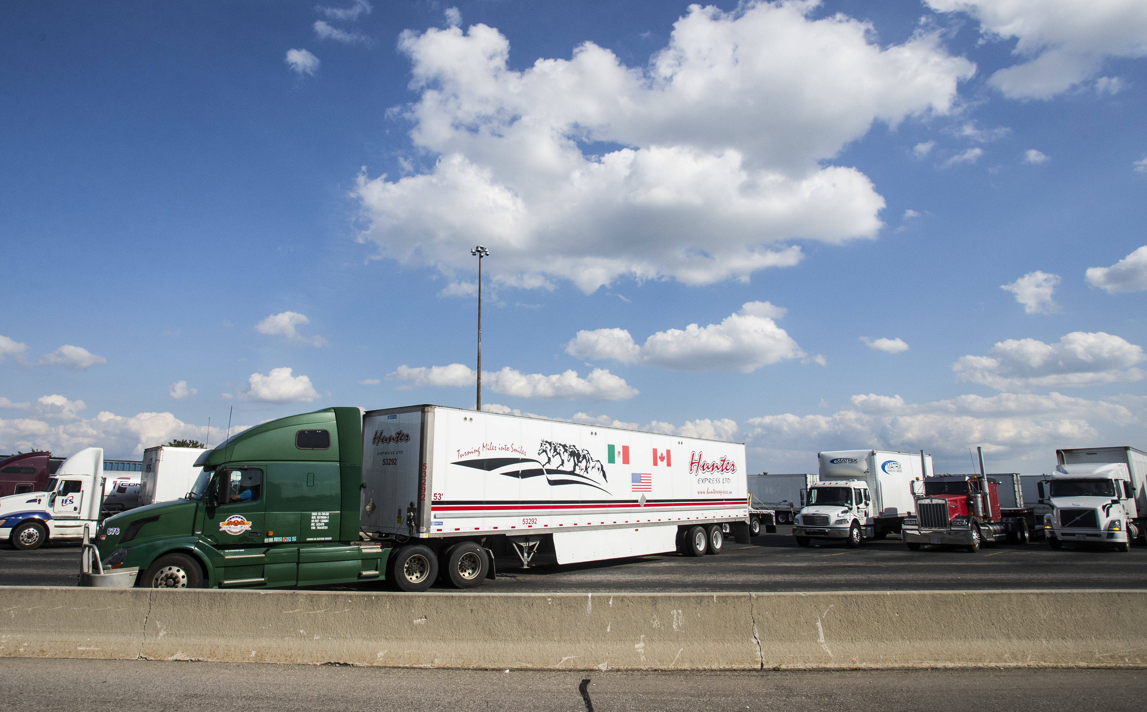 加拿大与美国国旗的长途货车(前)驶离401号高速公路的一处服务区