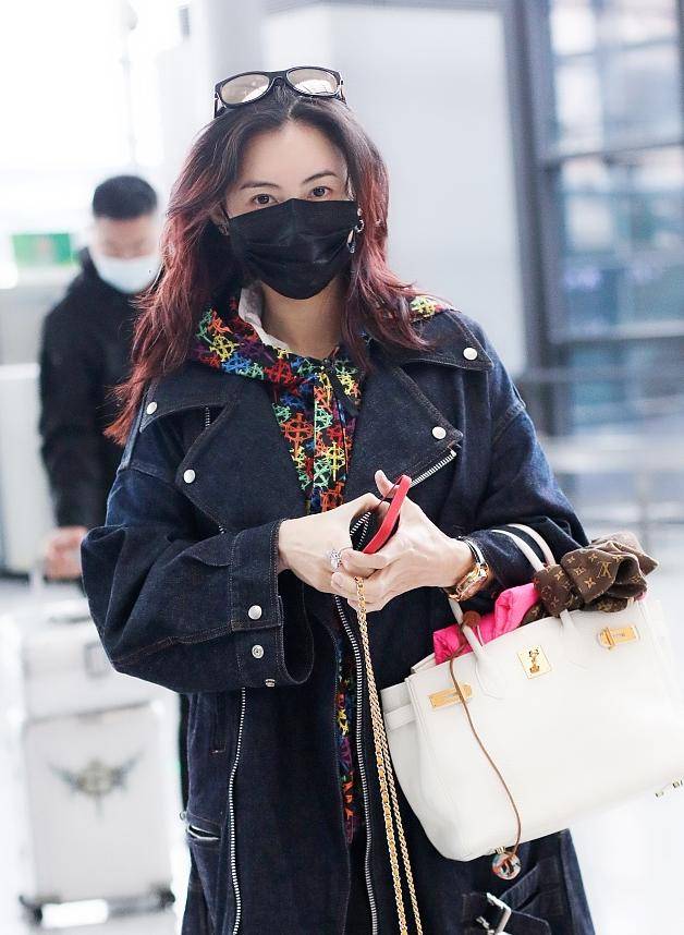 张柏芝穿着一件牛仔风衣外套,里面一件花色的卫衣,戴着墨镜和口罩
