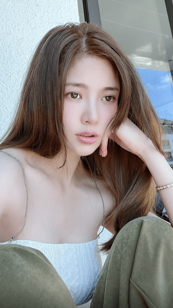 照片中王灿化着淡雅的妆容,脸上微微泛红,用手托着脸颊,眼神看着前方