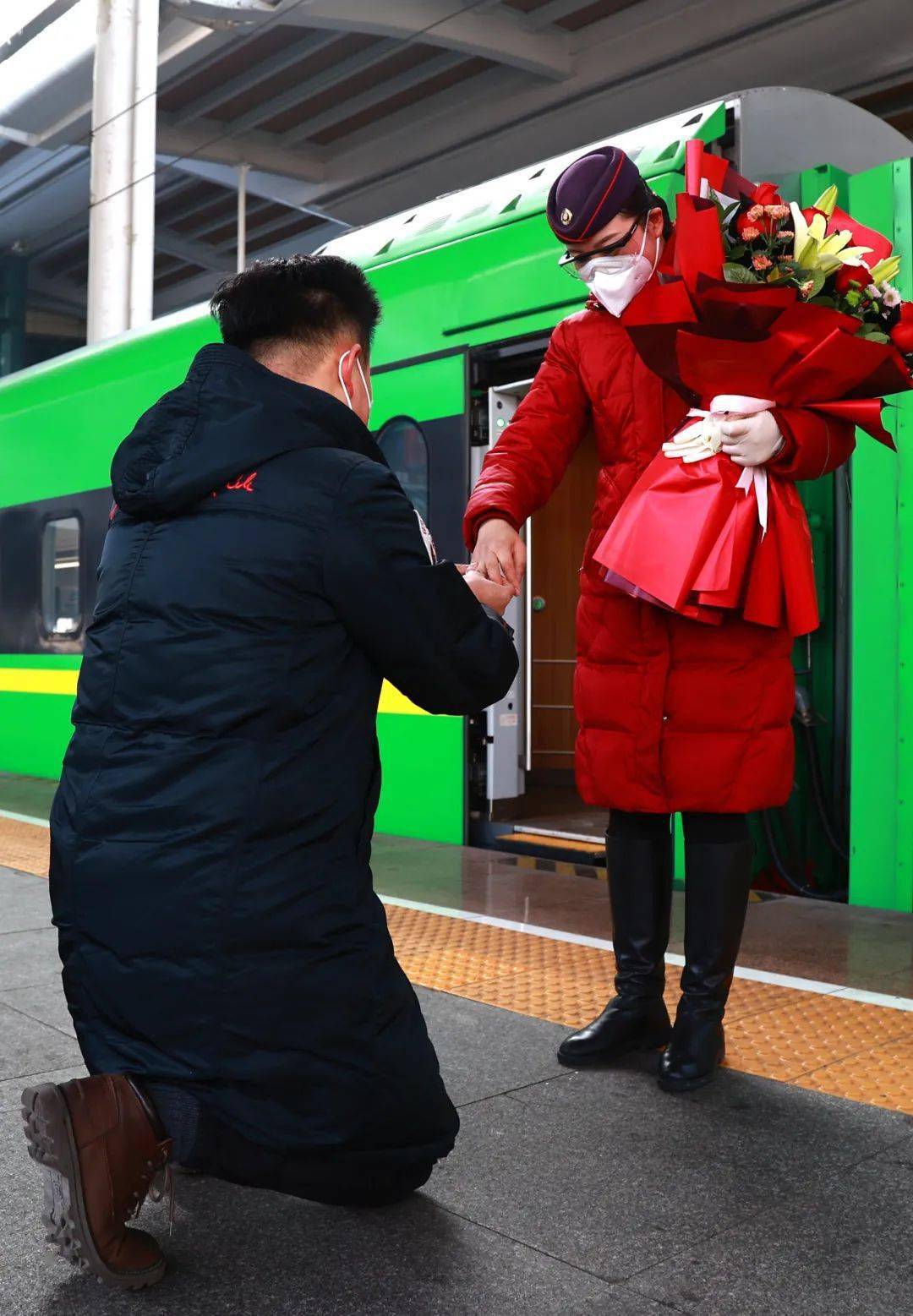 在乌鲁木齐站站台上路凯旭手捧着玫瑰百合组成的花束单膝跪地大声