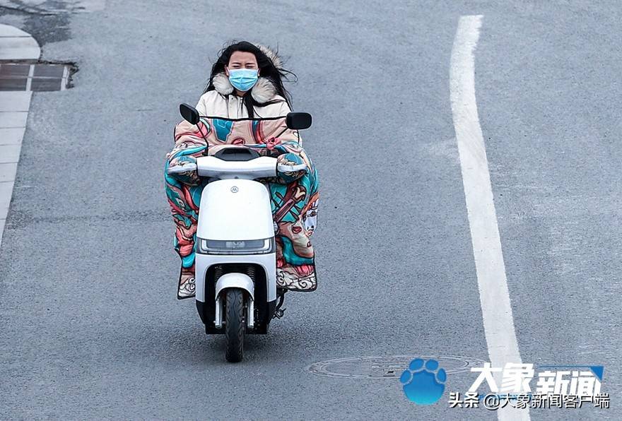 騎電動車在冷風中穿行確實需要勇氣身穿棉服的大媽在冷風中過馬路塑料